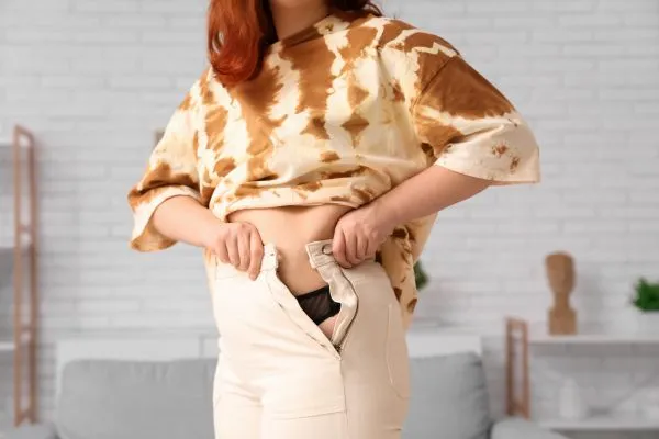 Image of woman trying to do her trousers up after pregnancy weight gain Dumfries